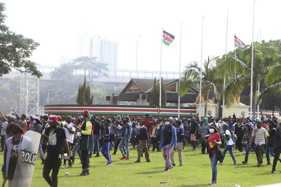 25日、ケニアの首都ナイロビで国会の敷地内を歩くデモ参加者（AP＝共同）