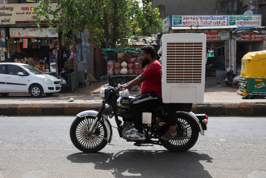 夏が始まったばかりの北半球各地が現在、猛暑に襲われて死者も出ており、昨年を超えて過去２０００年で熱い夏が訪れる兆候かもしれない。写真はバイクでクーラーを運ぶ男性。インドで５月撮影。（2024年 ロイター/Amit Dave/File Photo）