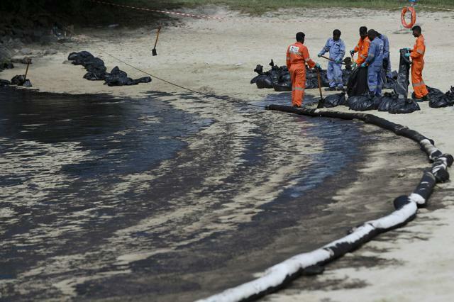 シンガポール南部セントーサ島で2024年6月16日、海岸に漂着した油の処理に当たる人々=AP