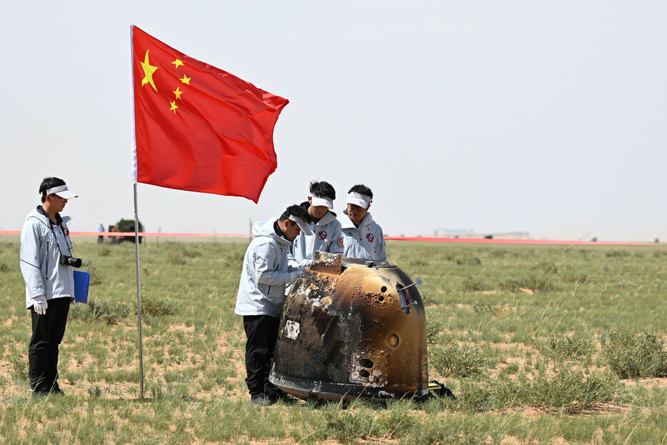 ２５日、世界で初めて月の裏側の土壌試料を採取した中国の無人探査機「嫦娥６号」が、地球に帰還した。内モンゴル自治区にパラシュートで落下し、駆け付けた人員が中国国旗を立てた。（ＥＰＡ時事）