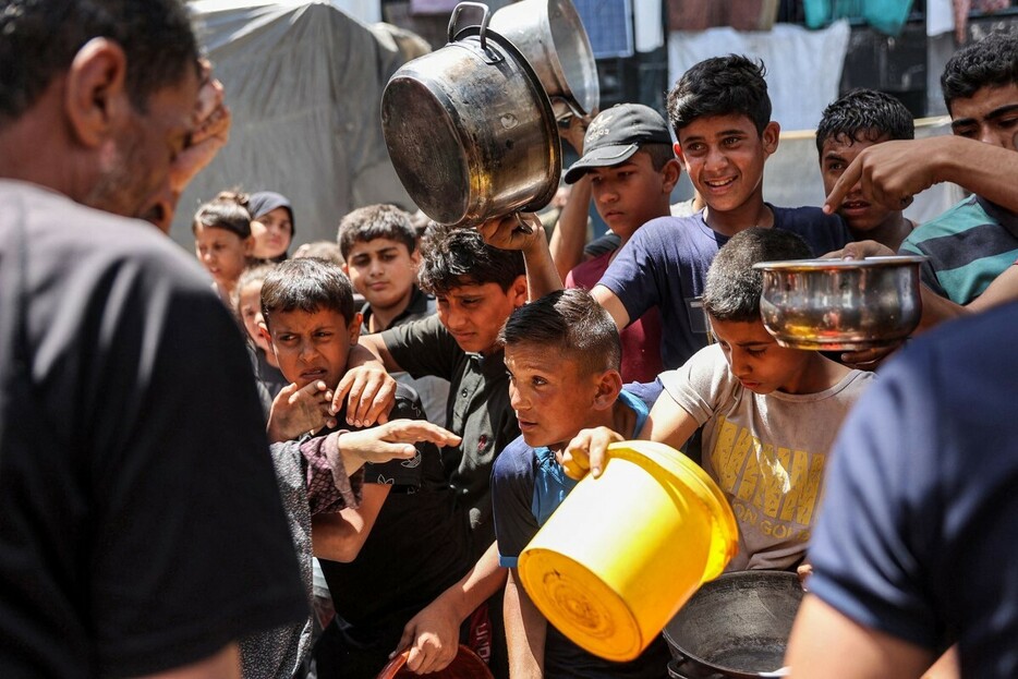 食糧援助を求めて並ぶ子どもたち＝１３日、パレスチナ自治区ガザ地区北部のジャバリヤ難民キャンプ
