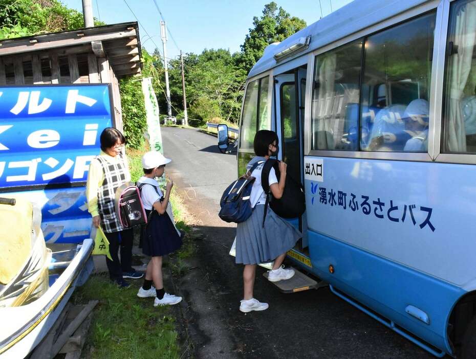 コミュニティーバス廃止に伴い町内で運行するスクールバスへ乗り込む生徒ら＝７日午前７時４０分ごろ、湧水町木場