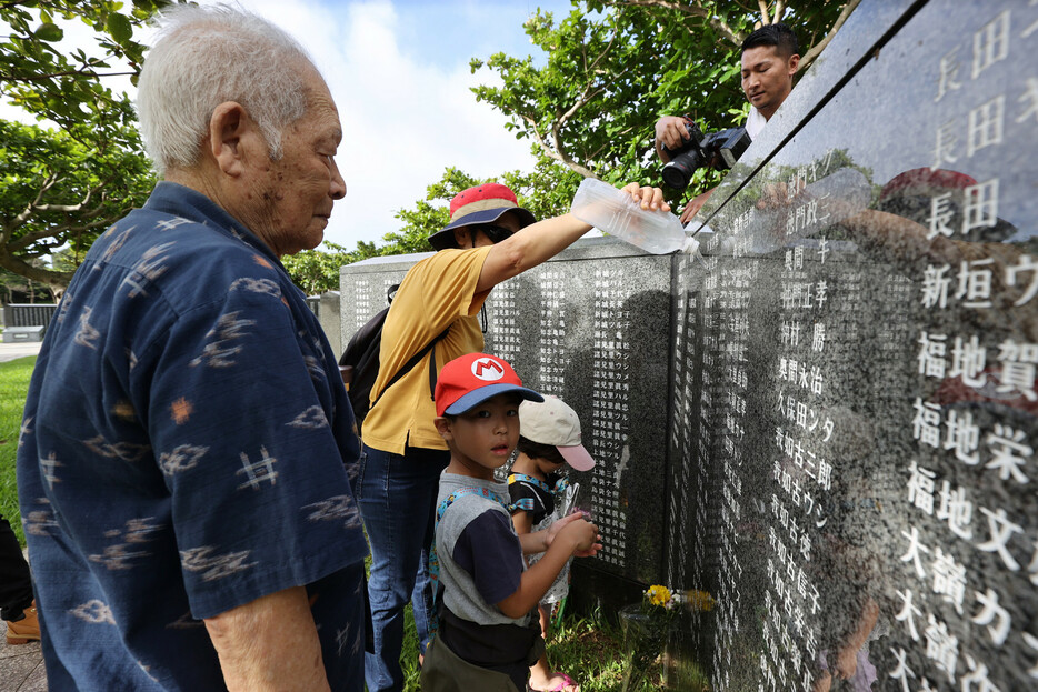ひ孫らと「平和の礎」を訪れた男性＝２３日午前、沖縄県糸満市の平和祈念公園