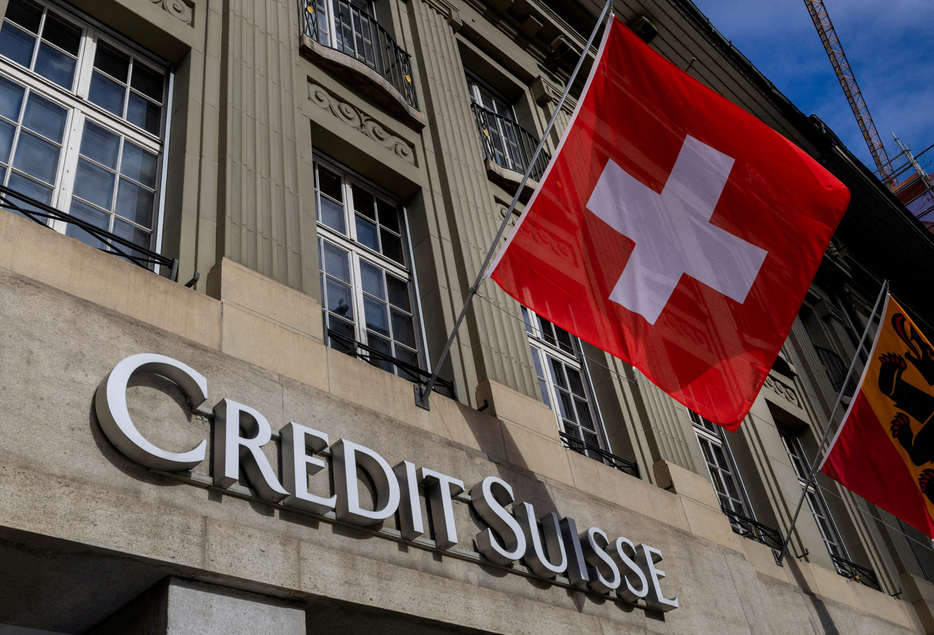 　６月１１日、スイスの金融大手ＵＢＳと同行が買収したクレディ・スイスのスイス事業の合併が早ければ７月１日にも完了する可能性がある。写真は、クレディ・スイスのロゴとスイス国旗。２０２３年１１月ベルンで撮影（２０２４年　ロイターDenis Balibouse）
