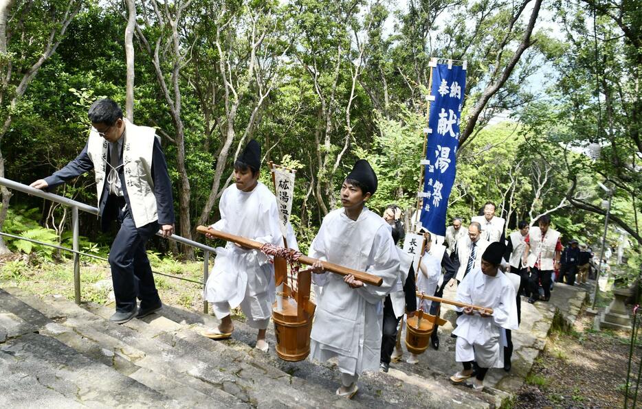 山神社で営まれた「献湯祭」で、朝一番の源泉からくみ上げた「一番湯」を運ぶ関係者＝1日、和歌山県白浜町