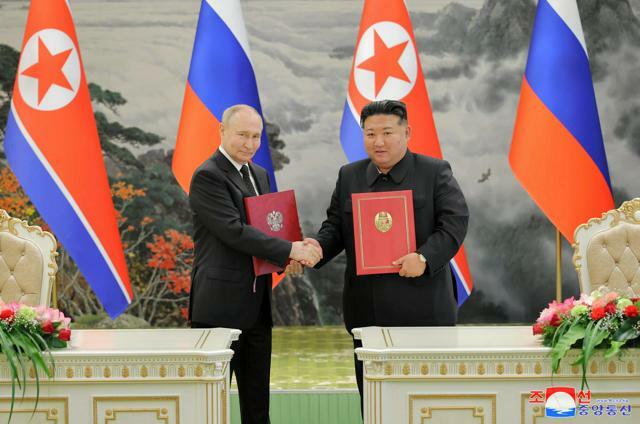 平壌で2024年6月19日、包括的戦略パートナーシップ条約に署名し、握手する金正恩総書記（右）とロシアのプーチン大統領。朝鮮中央通信が配信した=朝鮮通信