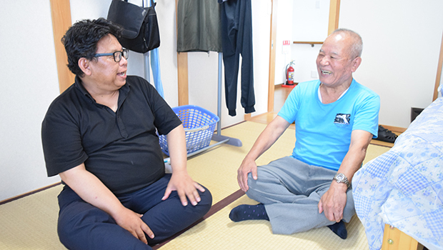 障害者GHいぶき寮の利用者と談笑する熊坂さん（左）