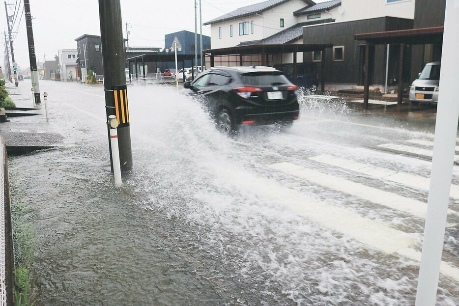 大雨で用水があふれ、冠水した道路＝２３日午後２時４０分ごろ、高岡市石瀬