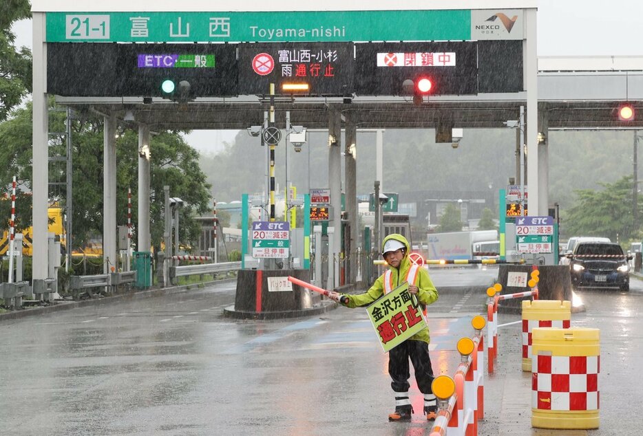 高速道路が通行止めになり、ゲート前で誘導する係員＝２３日午後３時ごろ、富山西ＩＣ