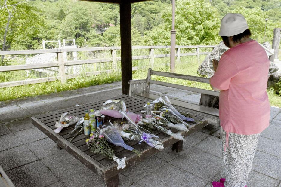 北海道留萌市の女子高生の殺害現場となった、旭川市の神居古潭地区にあるつり橋付近で手を合わせる女性＝15日午後