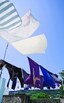 梅雨の晴れ間に青空の下で風に揺れる洗濯物＝４日、南城市奥武島（古謝克公撮影）