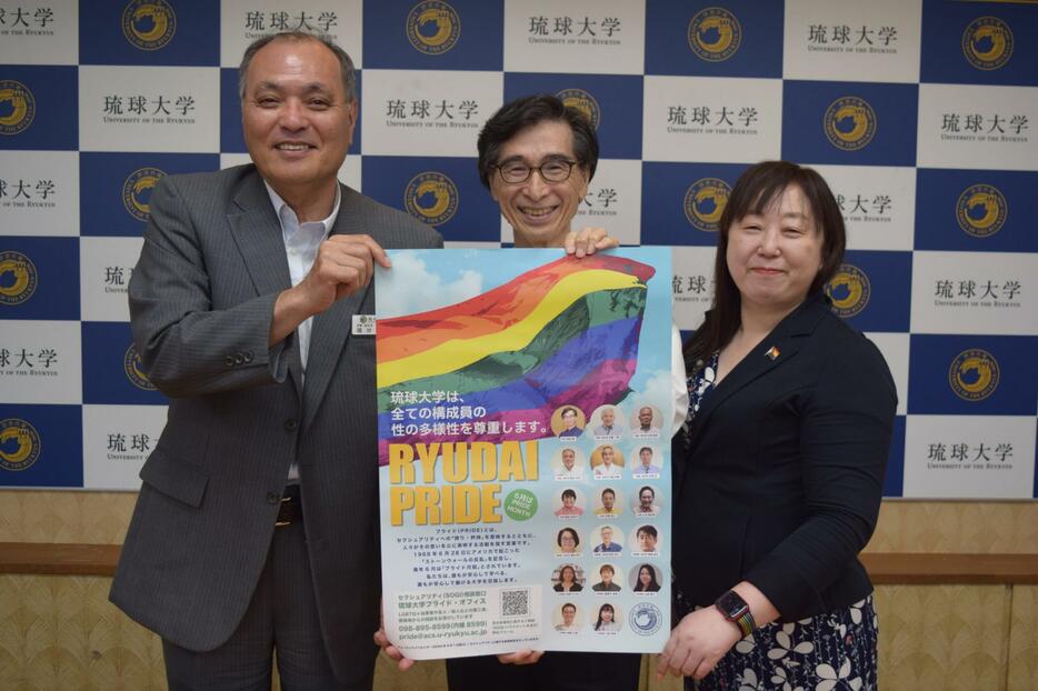 性の多様性尊重をＰＲするポスターを掲げる西田睦・琉球大学学長（中央）ら＝26日、西原町の琉球大学