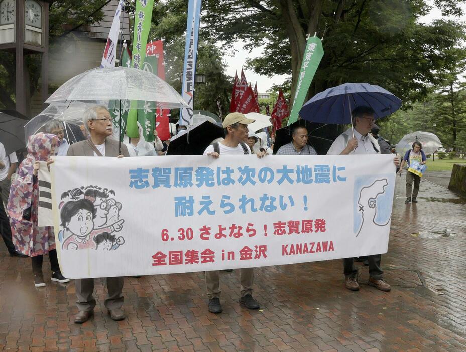 北陸電力志賀原発の廃炉を求める集会を終え、横断幕を掲げデモ行進する参加者＝30日午後、金沢市