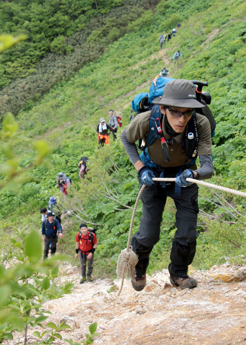 好天の下行われた夏油三山山開きで、牛形山の山頂を目指す参加者＝9日午前9時30分ごろ