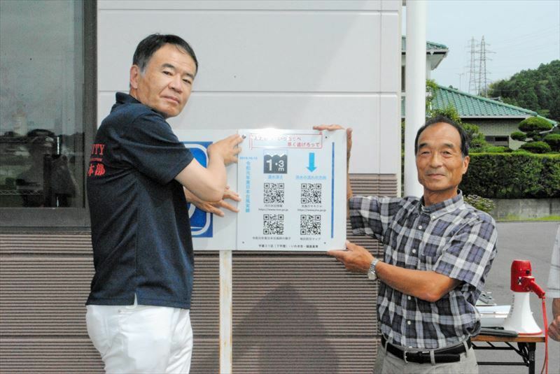 下平窪公民館にアナデジサイネージ看板を設置する松島部長（左）と江尻区長