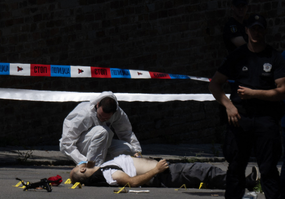 セルビア・ベオグラードのイスラエル大使館前で、負傷者の容体を調べる警察官（2024年6月29日撮影）。【翻訳編集】 AFPBB News