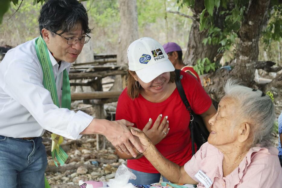 2024年5月、フィリピンのリナパカン島で、日系2世の80代女性（右）と面接する花田貴裕総領事（左）（共同）