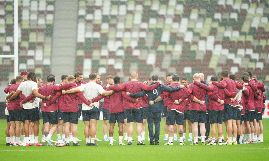 雨の中、ピッチ上の色々な場所で円陣を組み話し合うイングランドの選手たち（撮影・垰建太）
