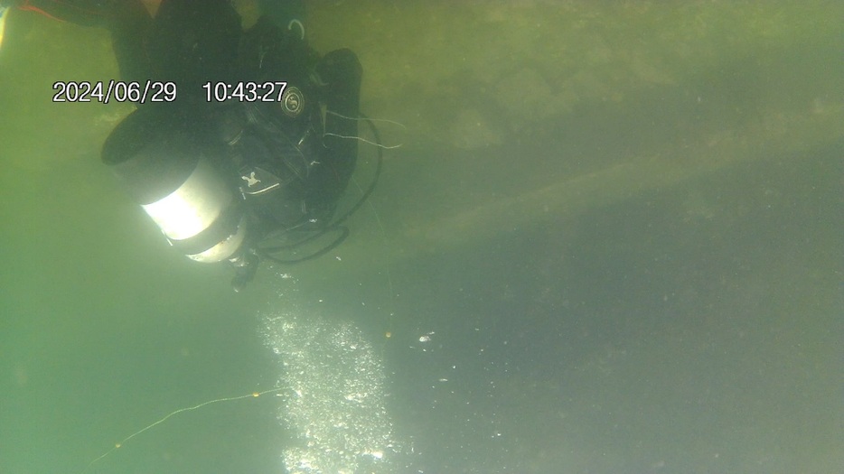 海底のごみを拾い集めるダイバー