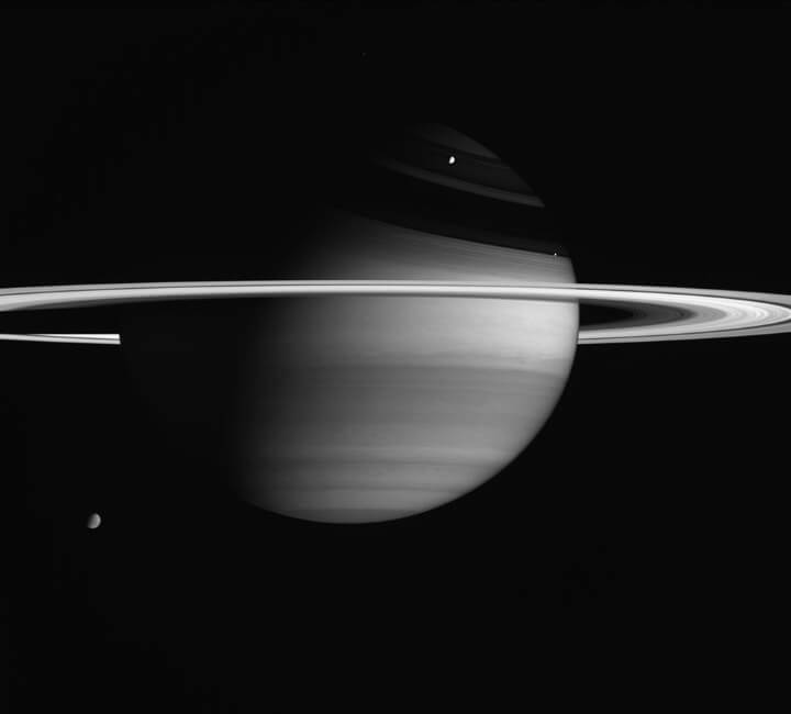 エンケラドゥスは反射率が高く、土星の衛星の中で最も明るい表面を持っている。ここでは、画像の右側のリングの真上にエンケラドゥスを見ることができる