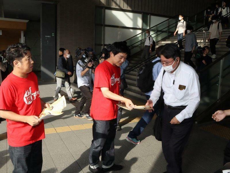 岡山県の2024年度の施策を伝える「予言の書」を配る井口さん（左）と河本さん（中央）