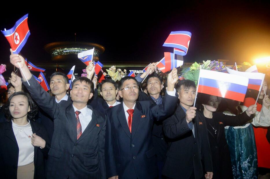 2023年10月、平壌国際空港で北朝鮮とロシアの国旗を振る人たち（共同）