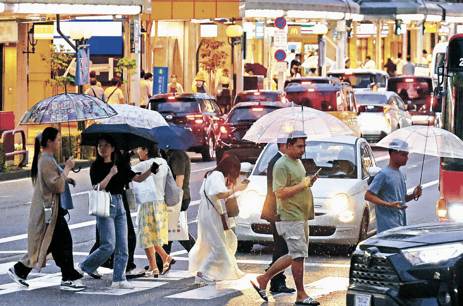 降り出した雨の中、目的地へ急ぐ人たち＝金沢市片町２丁目