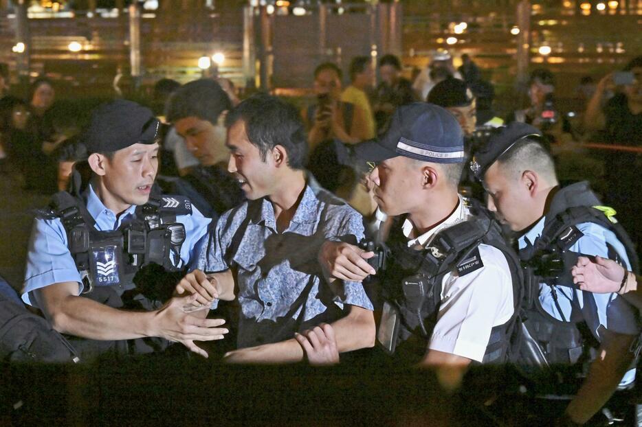 香港のビクトリア公園で警察官に身柄を拘束される飯村行雄さん（左から2人目）＝4日（共同）
