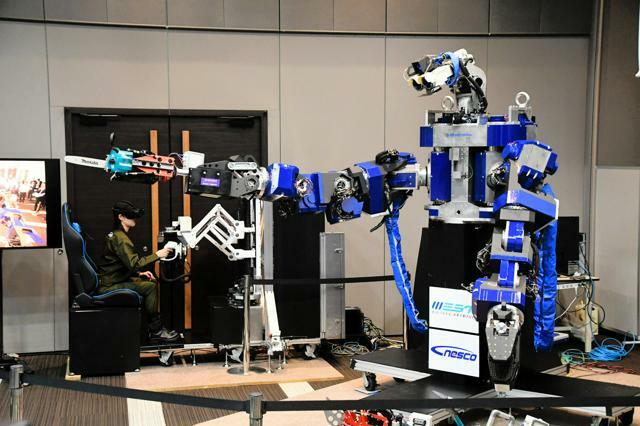 JR西日本などが開発した「人型ロボット」は、専用の操縦桿（かん）で人が操作する。アームにチェーンソーを取り付けて木の伐採もできる=2024年6月27日、東京都港区、中村建太撮影