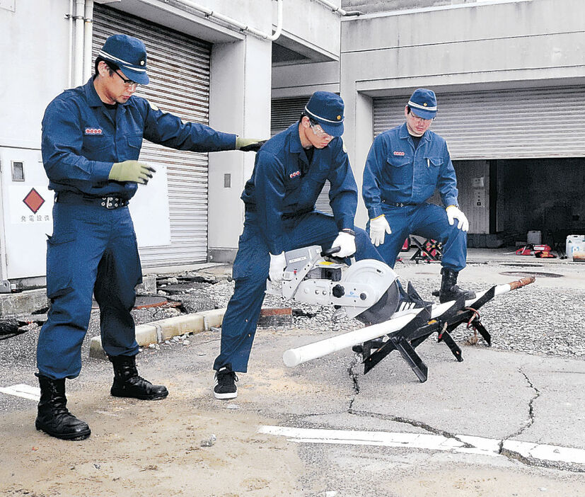 エンジンカッターで鉄製ポールを切断する署員＝２５日午前８時半、輪島署