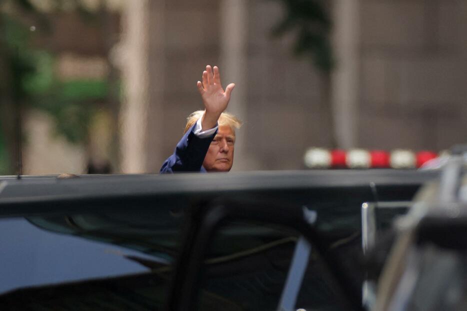 有罪評決を受けた翌日、トランプタワーの前で手を振るトランプ前米大統領＝5月31日、米ニューヨーク市（ロイター＝共同）
