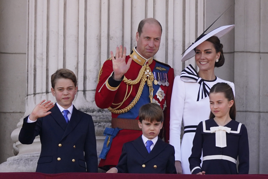 英バッキンガム宮殿のバルコニーで子どもたちと共に群衆に手を振るウィリアム皇太子（中央奥）とキャサリン皇太子妃（右奥）＝15日、ロンドン（AP＝共同）
