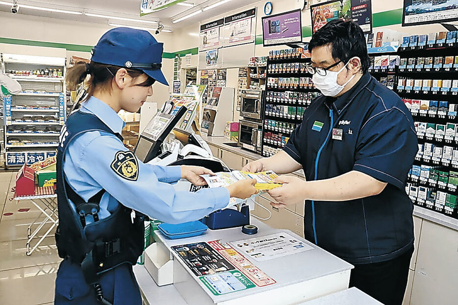 特殊詐欺への注意を促すチラシを店員に渡すタッグポリスの署員＝加賀市大聖寺南町