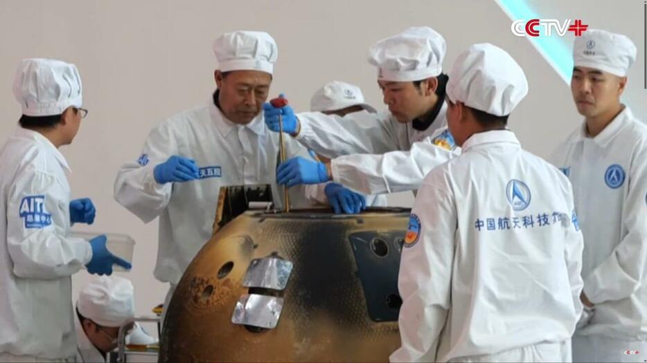 2024年6月26日に開催された引き渡し式で月探査機「嫦娥6号」の帰還機からサンプル保管容器を取り出す作業の様子。中国中央電視台がYouTubeで配信している動画から