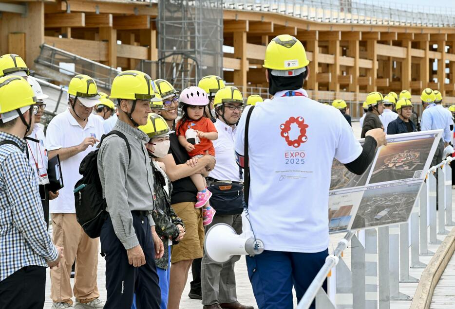木造巨大屋根「リング」の見学ツアーで、担当者から説明を受ける参加者＝30日、大阪市の夢洲