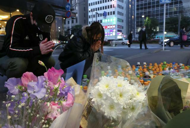 殺害された女性を悼み、花や飲み物が供えられた現場に手を合わせに来た男女=2023年2月8日、福岡市博多区、吉本美奈子撮影