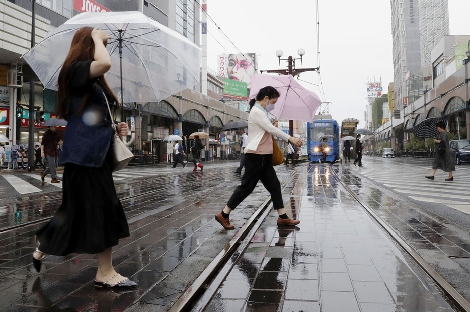 雨が降る鹿児島市内で、傘を差して歩く人たち＝20日