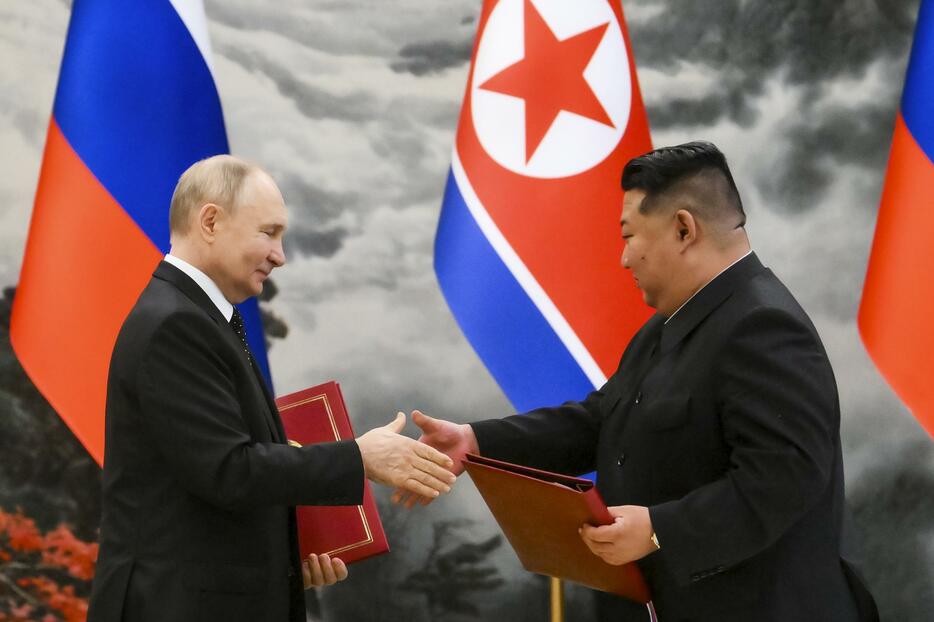 19日、北朝鮮・平壌での調印式で、文書を交換する金正恩朝鮮労働党総書記（右）とロシアのプーチン大統領（AP＝共同）