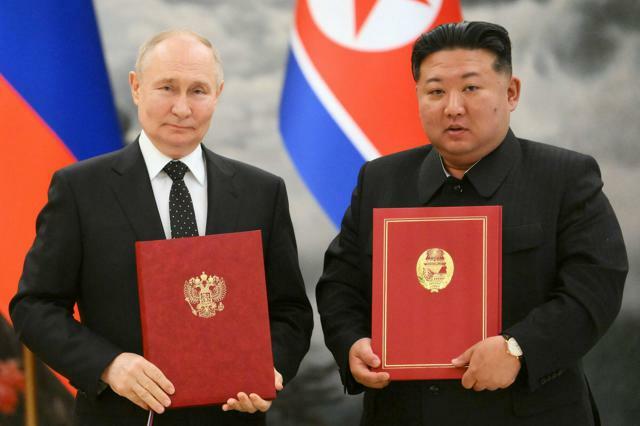 北朝鮮の平壌であった首脳会談後の署名式で19日、写真撮影に応じるロシアのプーチン大統領（左）と金正恩総書記＝ロイター
