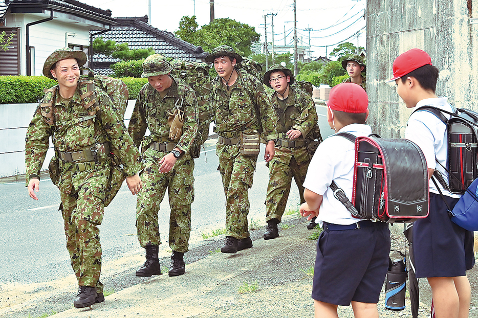 徒歩行進訓練の途中、下校中の小学生とあいさつを交わす陸自奄美警備隊の隊員たち＝20日、鹿児島県天城町