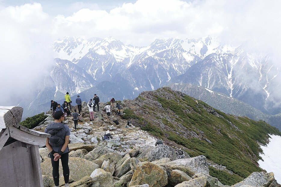 常念岳山頂で眺望を楽しむ登山客。ガスが立ち込めていたが、次第に展望が開け穂高連峰が見えてきた