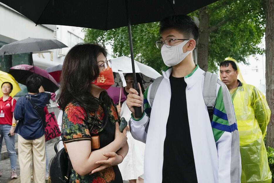 「高考」の受験会場前でチャイナドレス姿の保護者（左）と話す受験生＝7日、北京（共同）