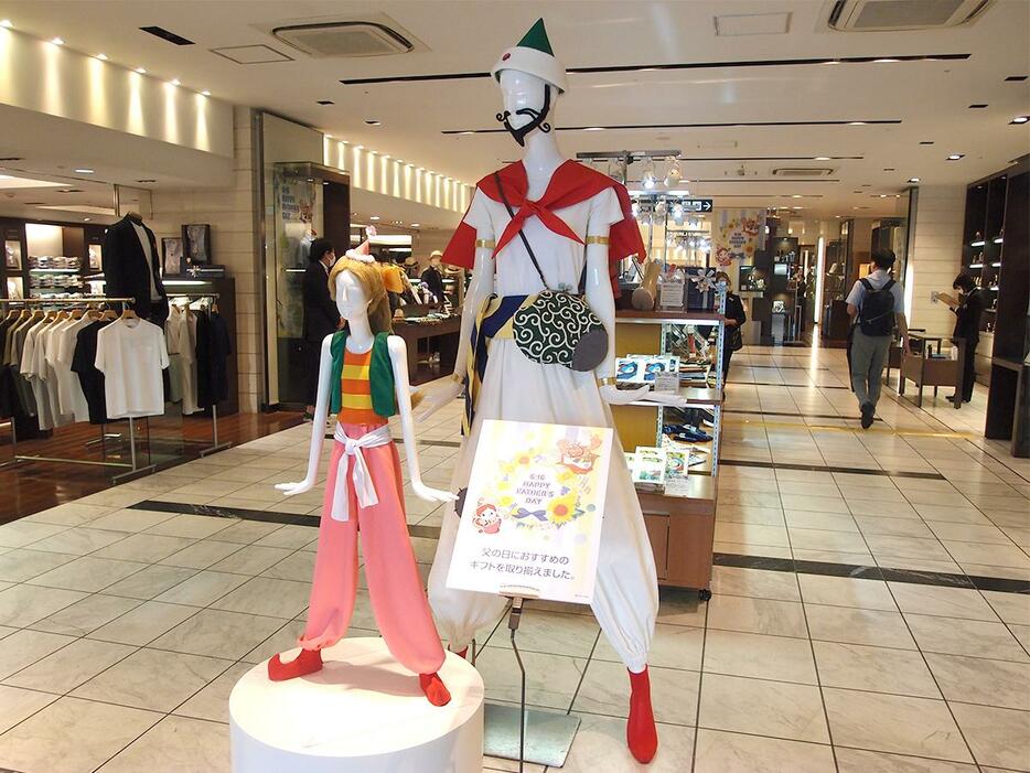 「ハクション大魔王」衣装の「ナナちゃん」ポーズのマネキンと、「アクビ」衣装の「ミナちゃん」を「父の日」特集コーナー前に設置する