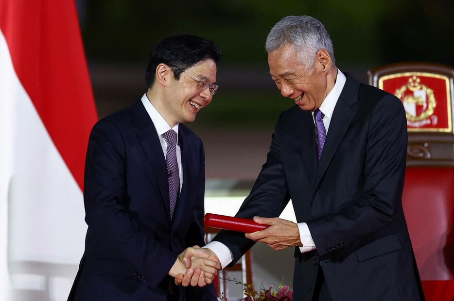 2024年5月15日、シンガポールのウォン新首相（左）と握手するリー・シェンロン氏（ロイター＝共同）