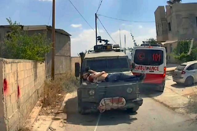 パレスチナ自治区ヨルダン川西岸ジェニンで2024年6月22日、ボンネットに負傷したパレスチナ人青年を縛り付けて走るイスラエル軍の車両。別の救急車の車載カメラの映像から=AP