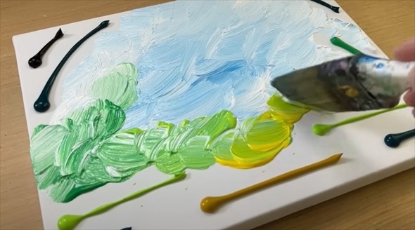 キャンバスに絵の具を置き、筆で色を混ぜていきます