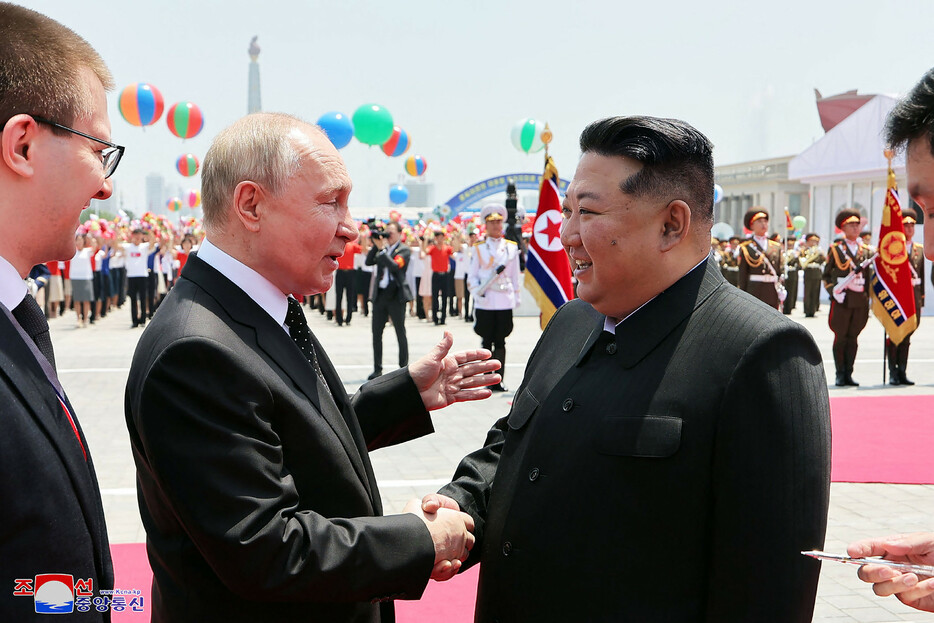 １９日、平壌の金日成広場でロシアのプーチン大統領（左）と握手する北朝鮮の金正恩朝鮮労働党総書記＝朝鮮中央通信が２０日配信