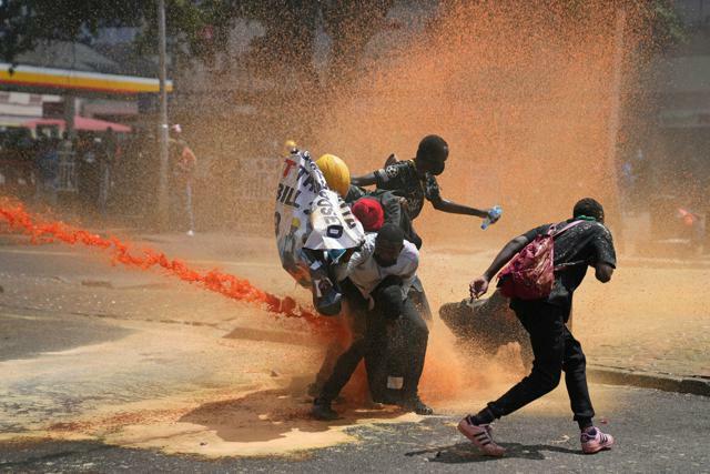ケニアの首都ナイロビで2024年6月25日、放水を受けて散り散りになるデモ隊=AP
