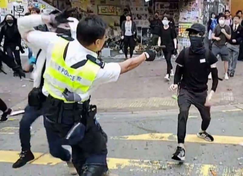 ２０１９年１１月、香港で抗議活動を行っていた若者（右）に銃を向ける警官。この後実弾を発砲した（香港メディア「丘品新聞」提供・共同）