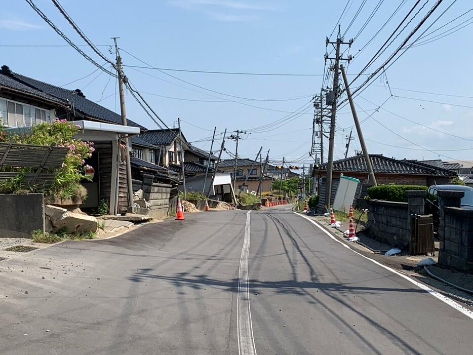 現在の石川県内灘町。液状化で道路にあふれた土砂は片付けられているが、住宅や電柱が傾いている状態は変わらない（本人提供）